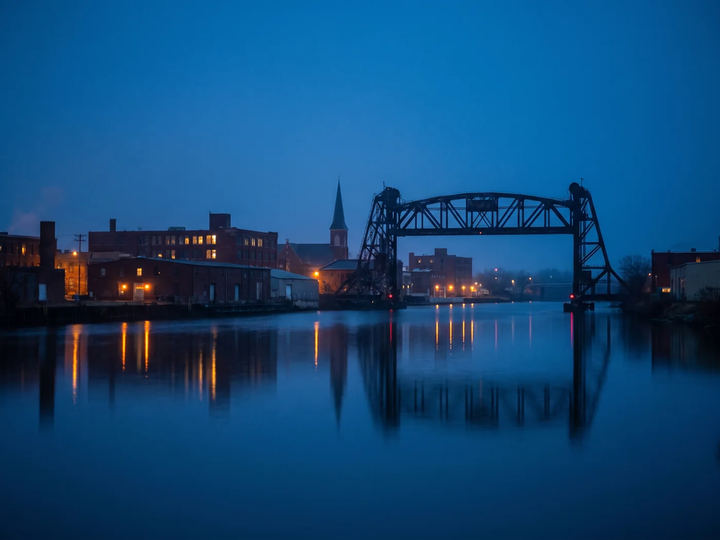A river and steel lift bridge running through a small city at dusk. Inspired Law Group serves Joliet and the surrounding Will County communities.
